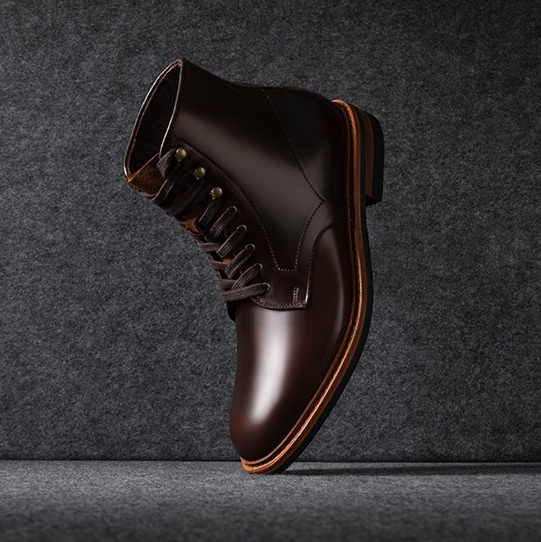 A side view of a black patent leather oxford dress shoe with the toe facing left.