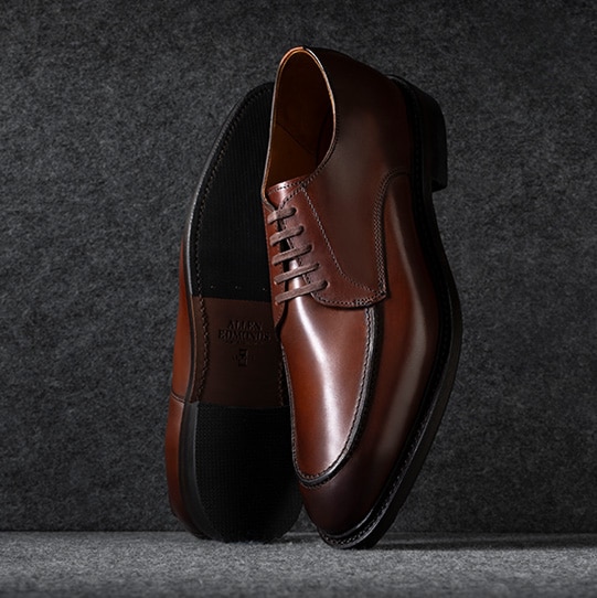 A side view of a brown suede men’s sneaker with the toe facing left.