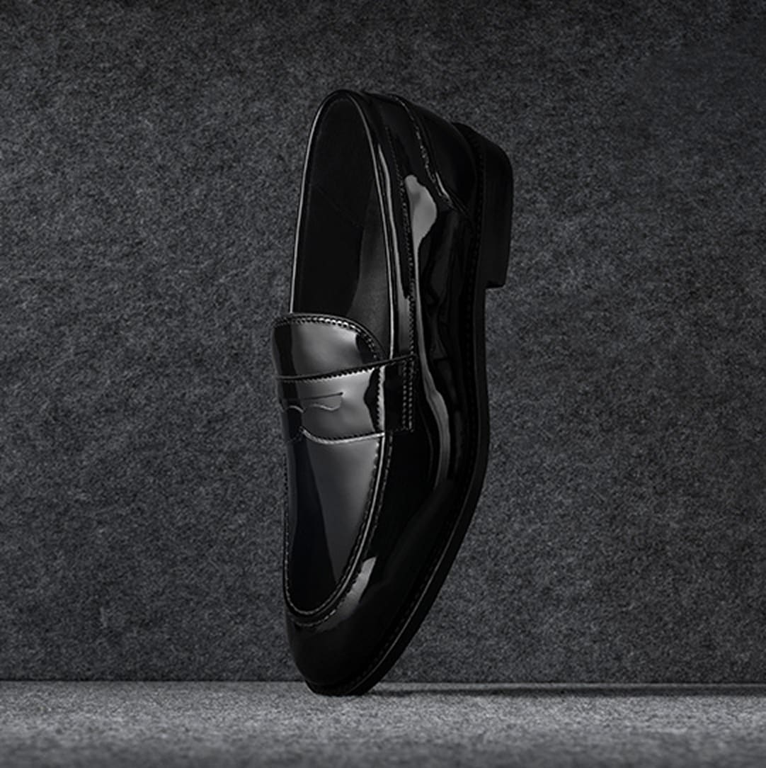 A side view of a black patent leather oxford dress shoe with the toe facing left.