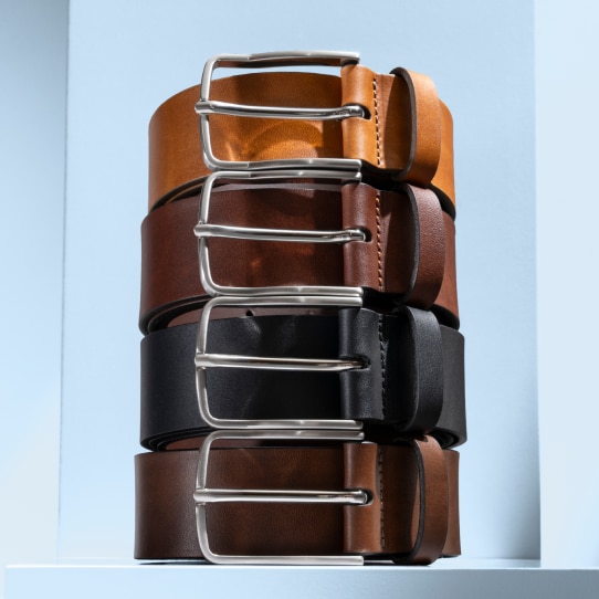 Stack of four handcrafted leather belts in tan, brown, black, and dark brown with silver buckles